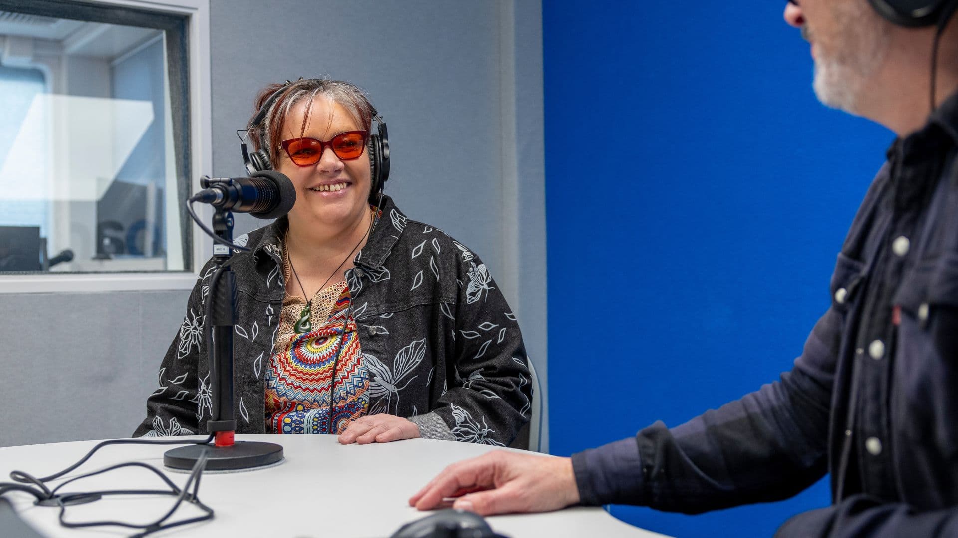 Leeann from APM NZ in a recording studio smiling with headphones on