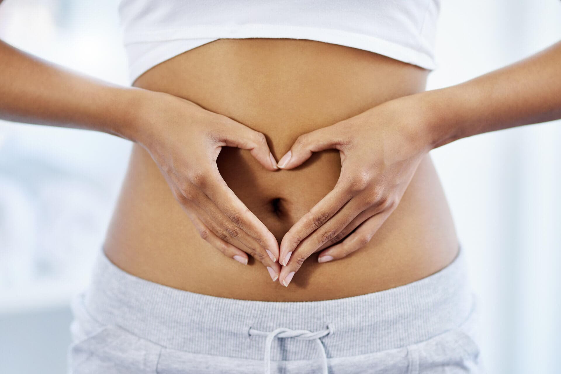 Woman making a heart shape with her hands in front of her tummy