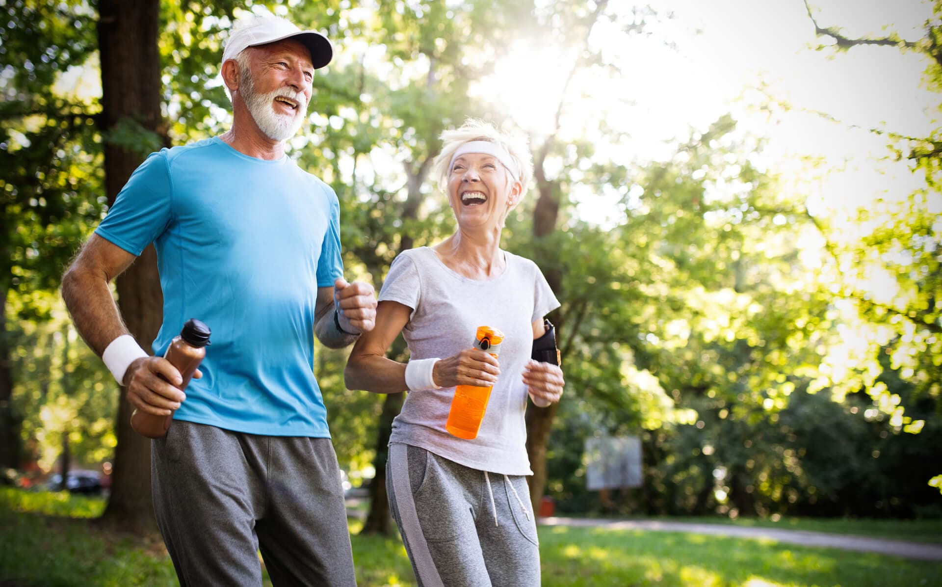 Older man and woman gleefully exercising in a bright park