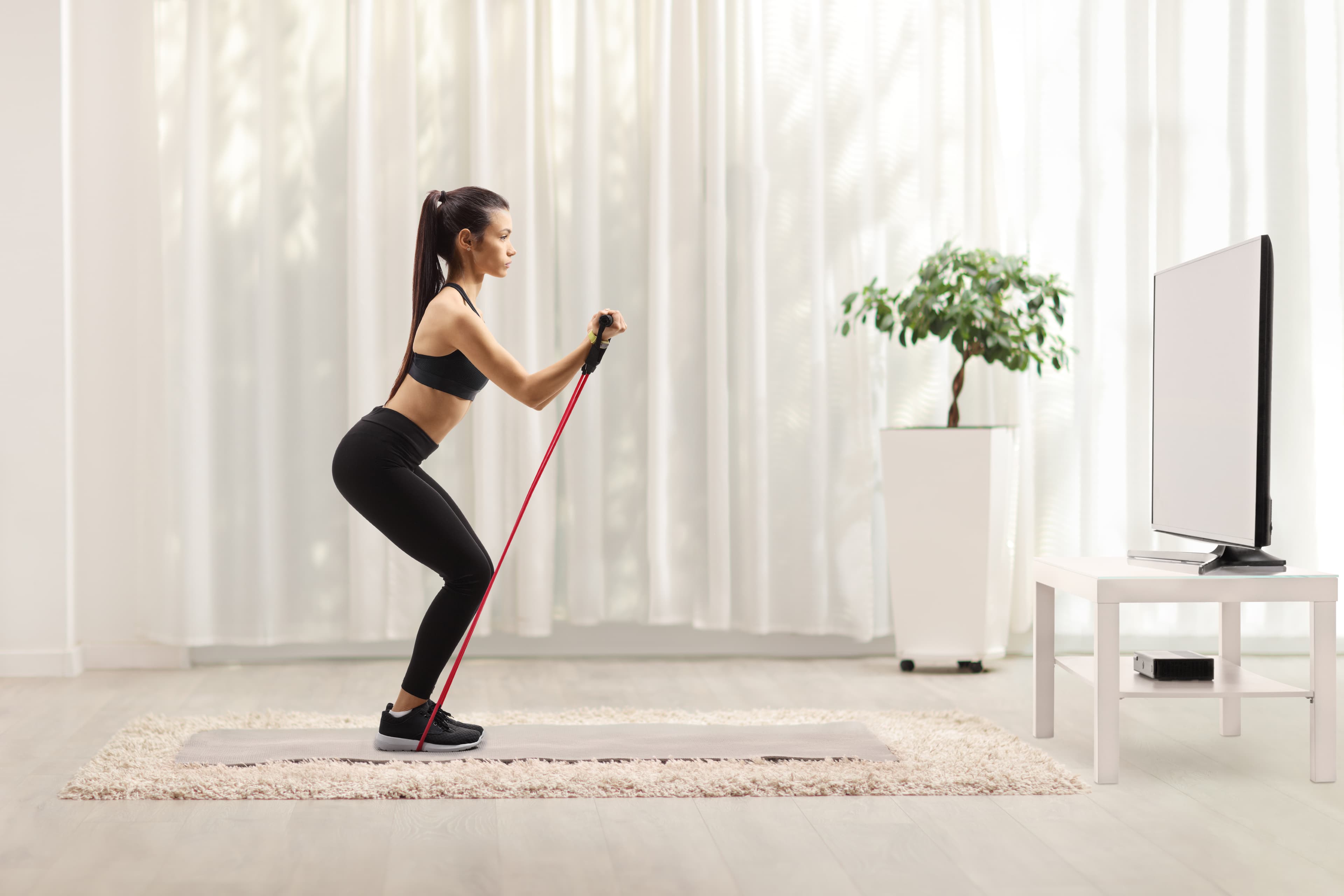 flex band squat stretch in front of TV