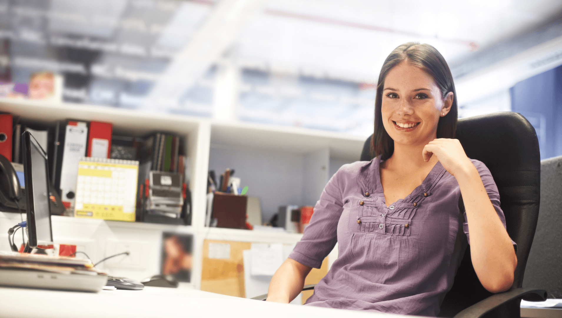 Woman sits smiling at a computer desk