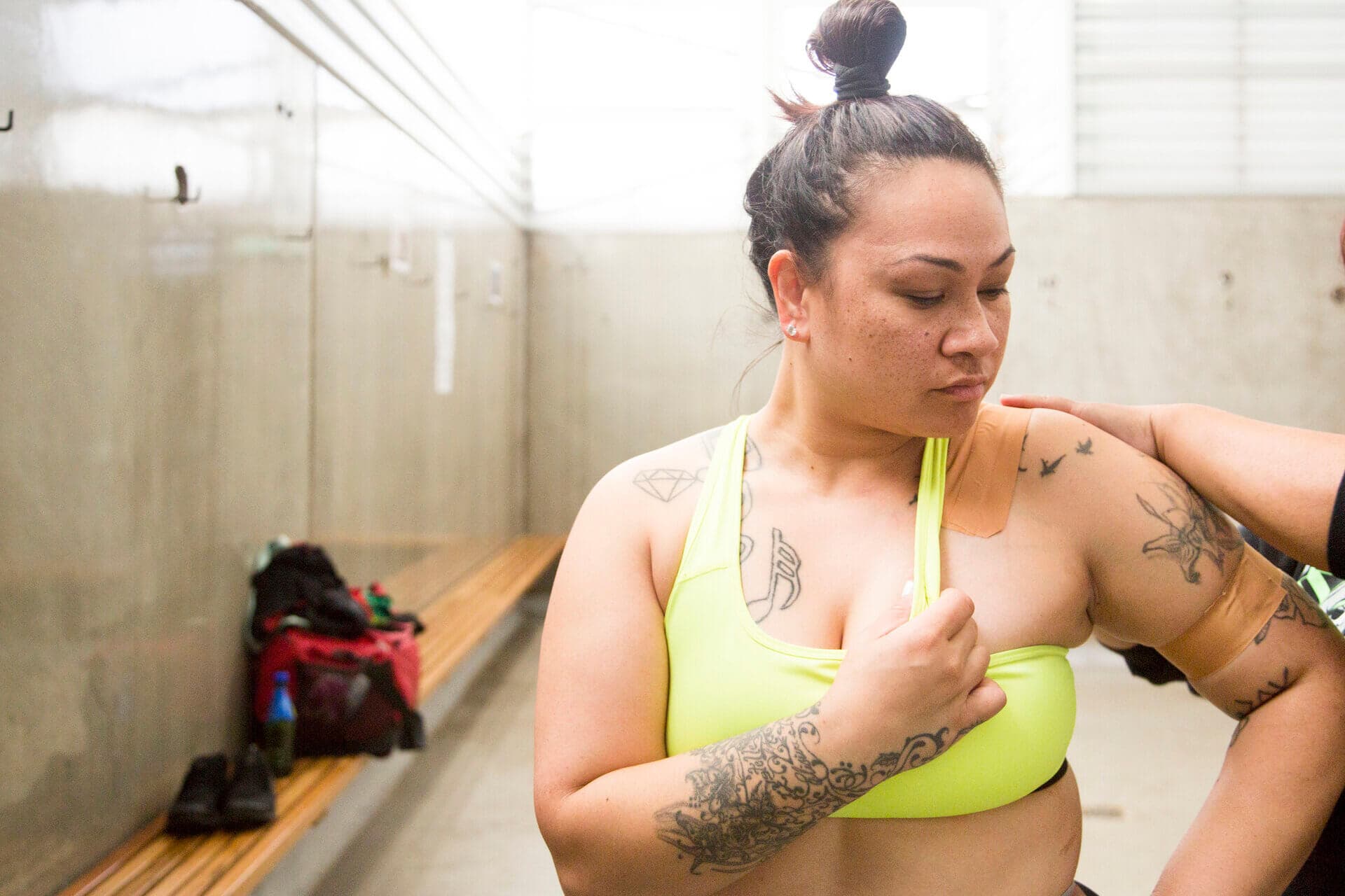 Lady in a change room holds bra strap as her shoulder and arm are taped