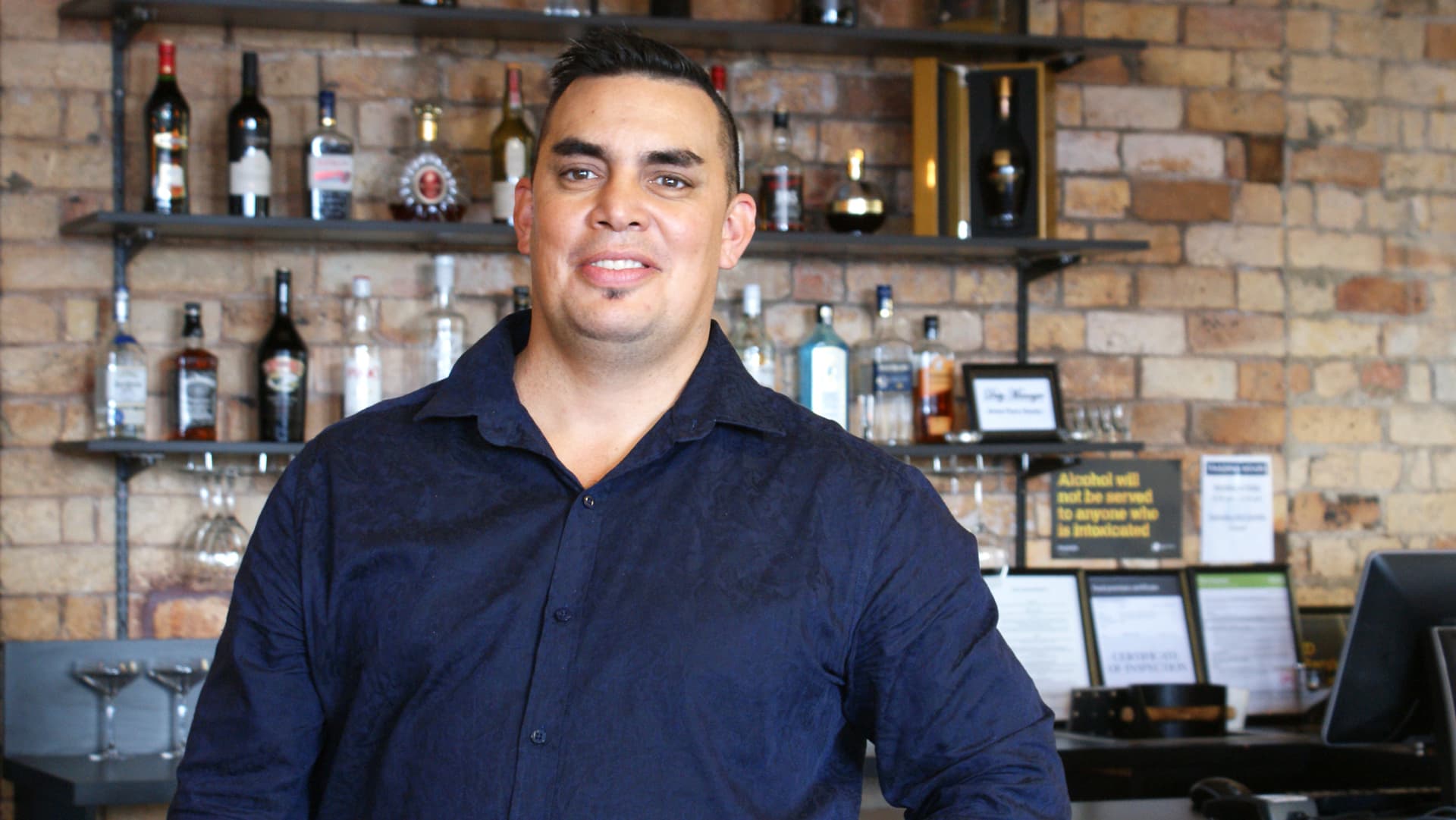 man behind a bar smiling