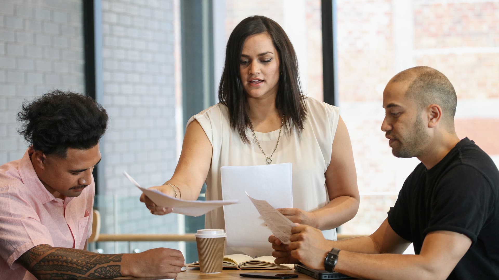 Woman handing out sheets of paper to a group at a meeting table