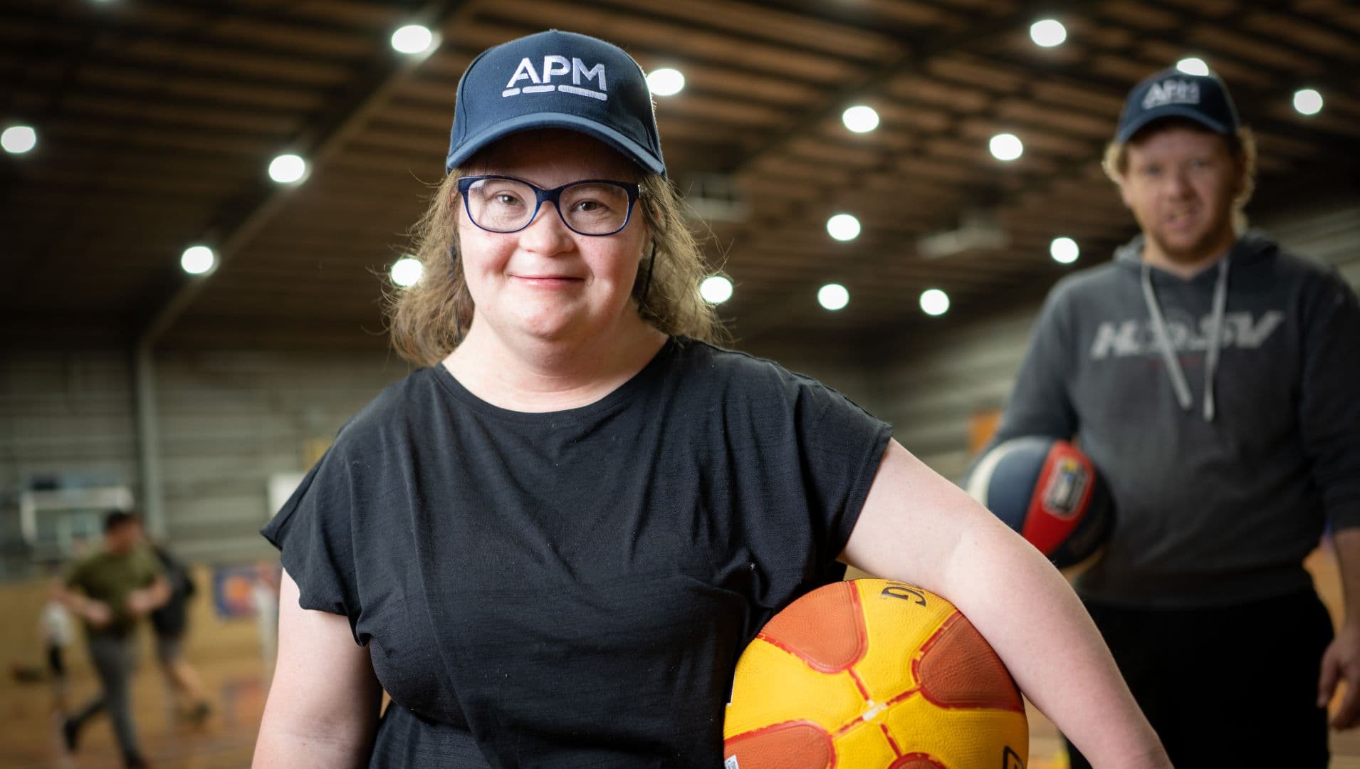 Girl with disability smiling with basketball and APM cap